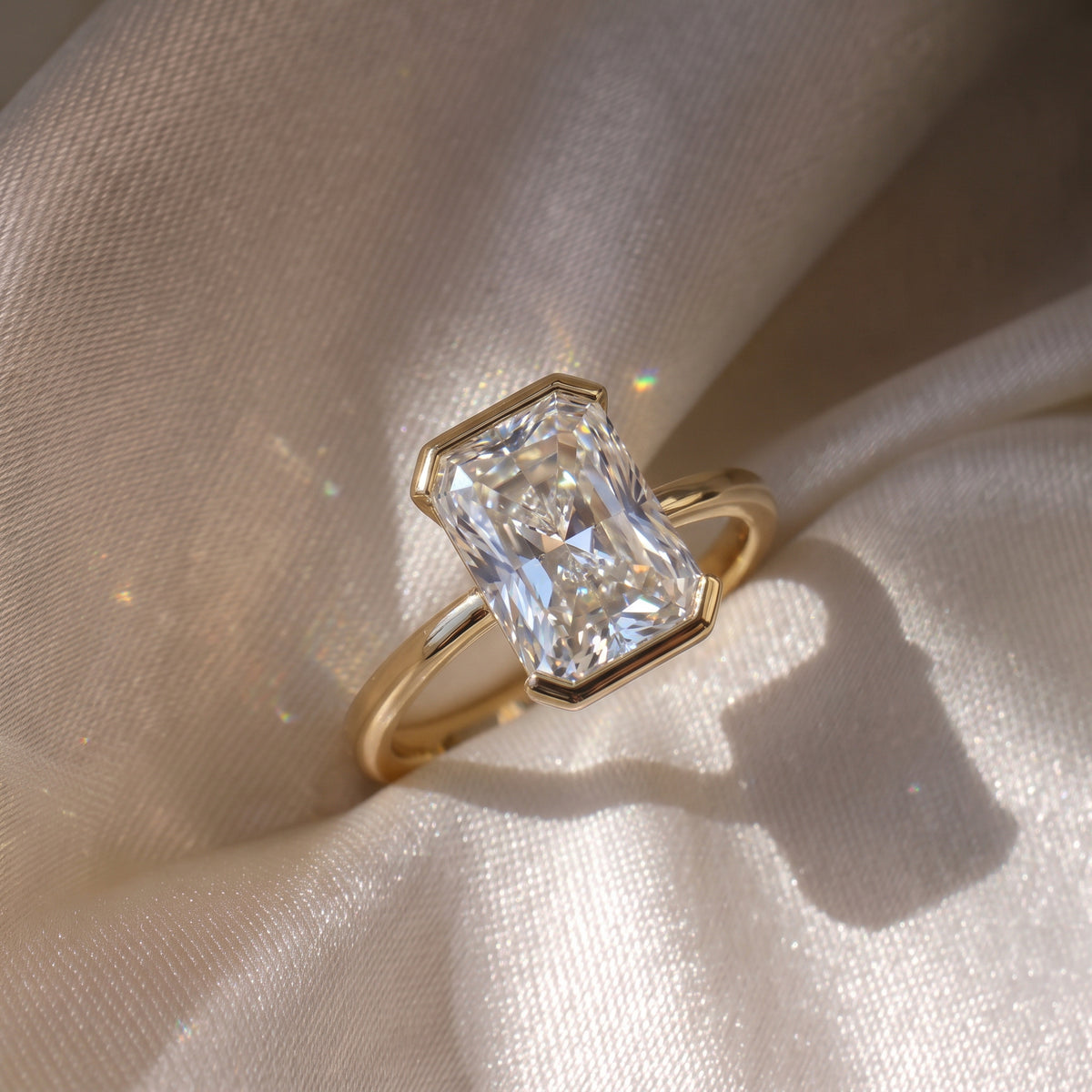 The Celine Ring — Radiant Half Bezel Solitaire Lab-Grown Diamond Engagement Ring in Yellow Gold on a luxurious silk fabric | The Jewel Concierge