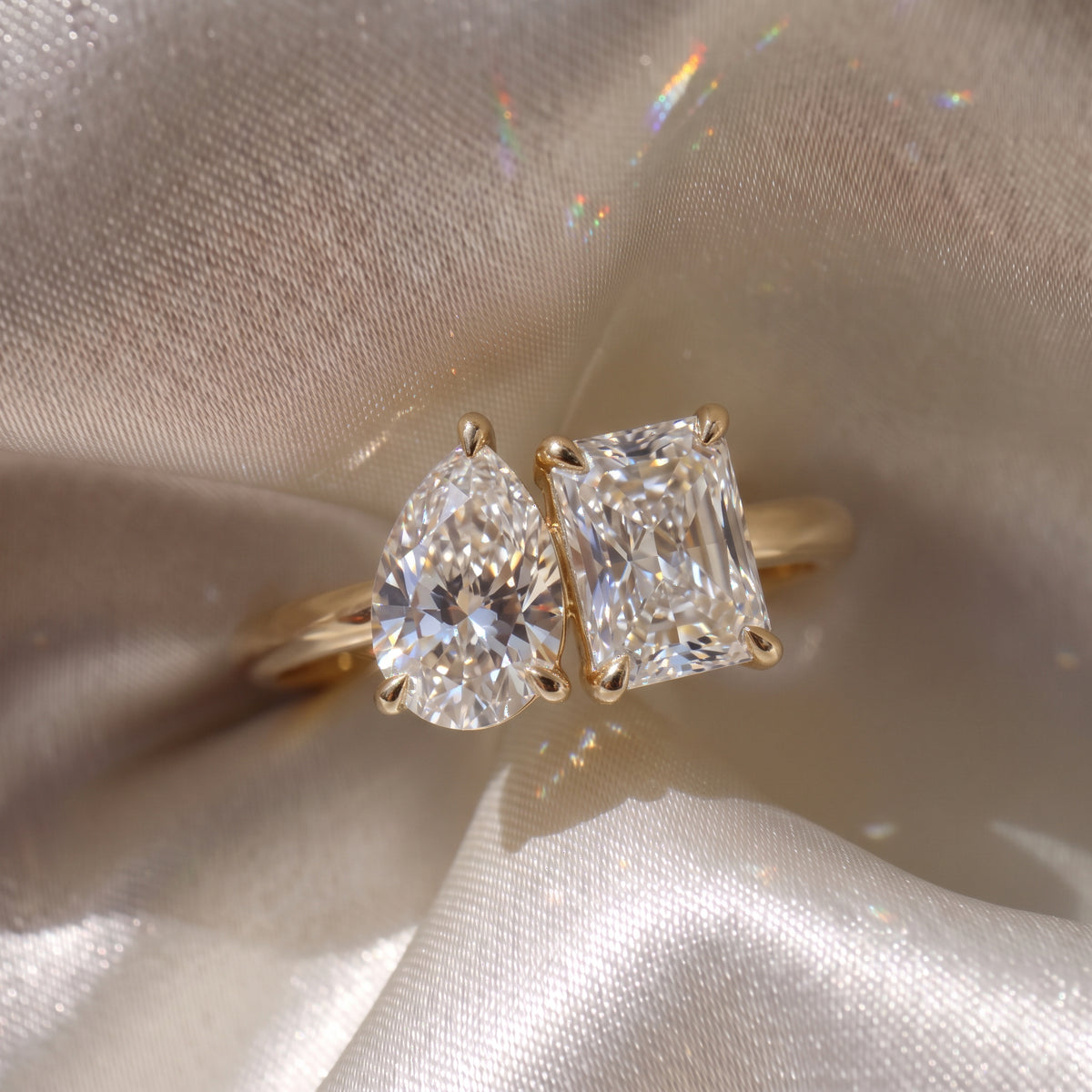 The Margot Ring — Pear and Radiant Toi Et Moi Lab-Grown Diamond Engagement Ring in Yellow Gold on a beige silk fabric | The Jewel Concierge