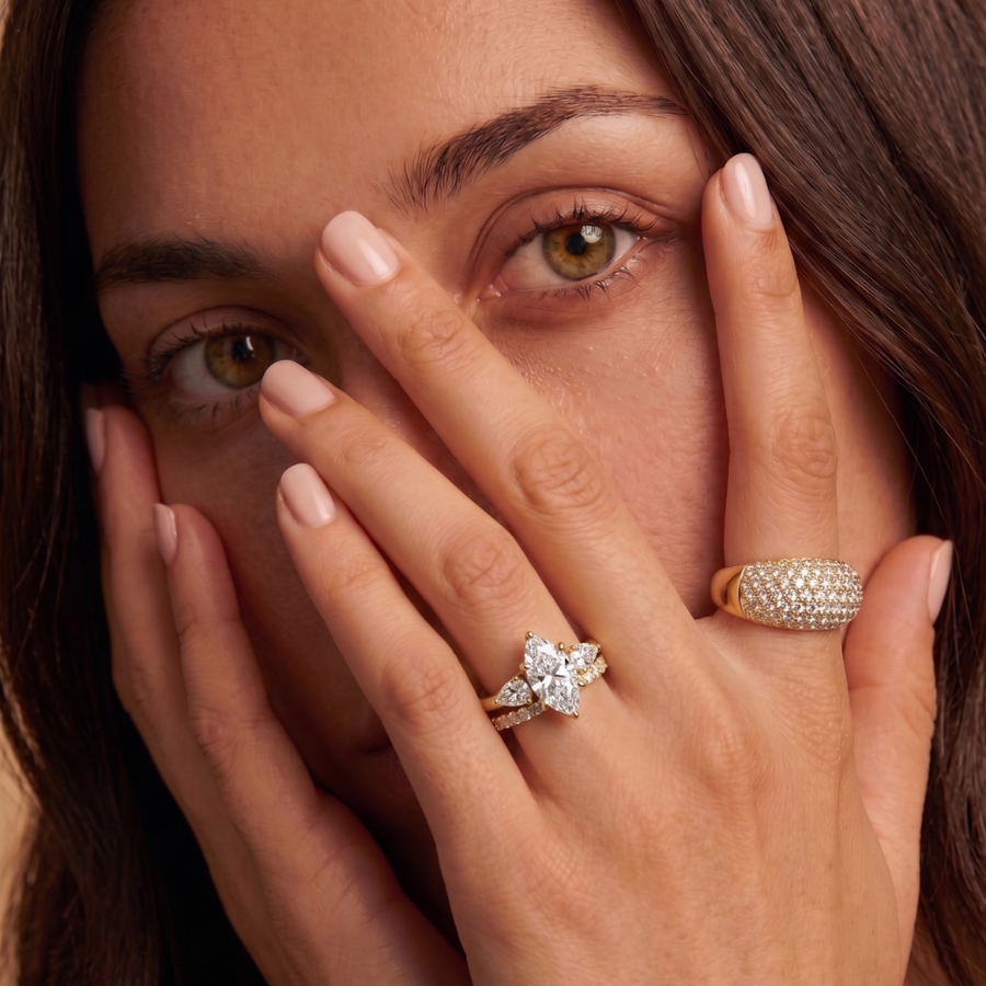 Close-up of a woman's hand Wearing a marquise cut lab-grown diamond engagement ring coupled with a lab-grown diamond wedding ring - The Jewel Concierge.