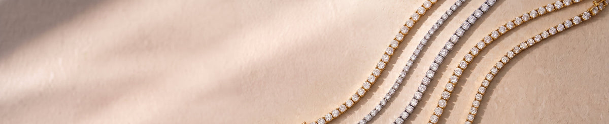 Signature Lab-grown Diamond Tennis Bracelets in yellow, white, and rose gold, elegantly laid against a warm beige background | The Jewel Concierge