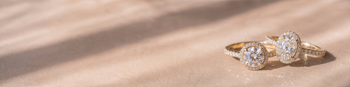 The Gemma Ring - Oval and round cut orbital halo against a warm beige background | The Jewel Concierge