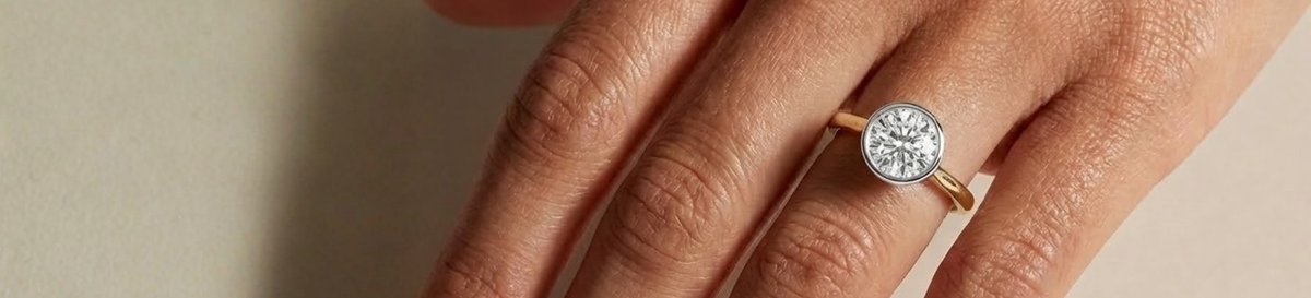 Close-up of a hand wearing a diamond ring on a neutral background | The Jewel Concierge