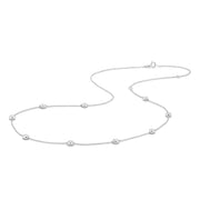 A delicate bezel by the yard gold chain necklace featuring nine small, round bezel-set clear lab-grown diamonds spaced evenly along the chain, displayed against a solid white background  - The Jewel Concierge