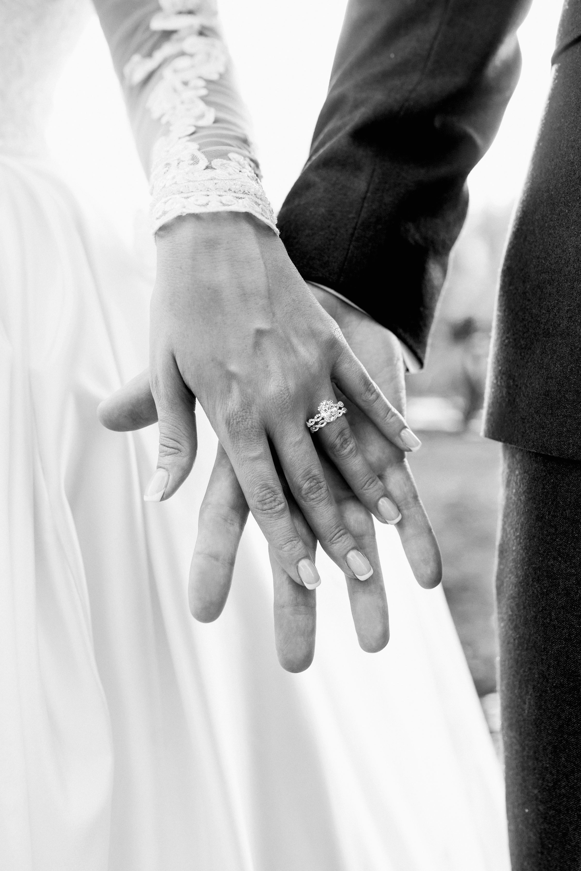 Black and white photo of bridge and groom holding hands with a wedding ring.