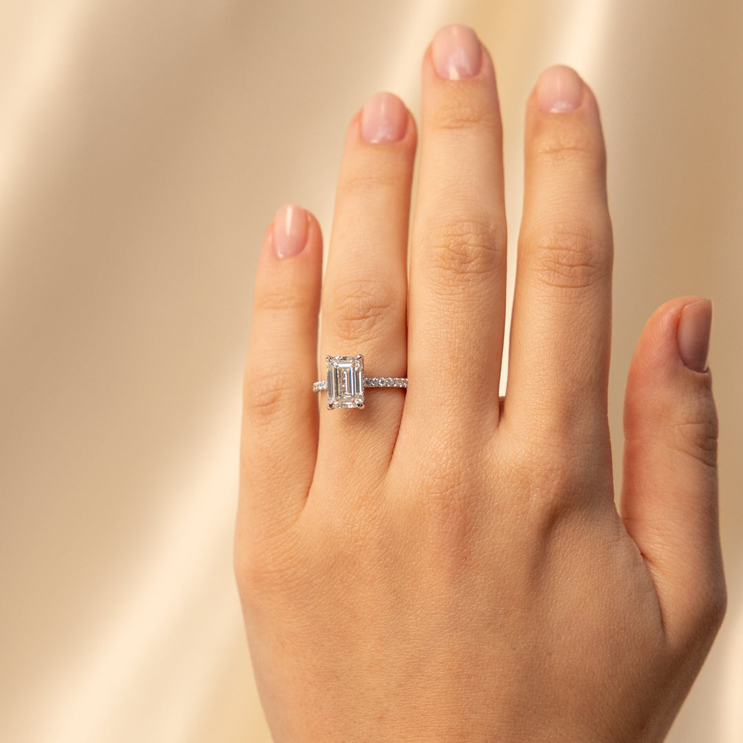 emerald solitaire engagement ring on a beige satin background