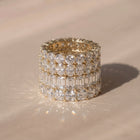 A close-up of four lab-grown diamond eternity rings in different shapes, resting on a warm beige surface with a soft shadow | The Jewel Concierge
