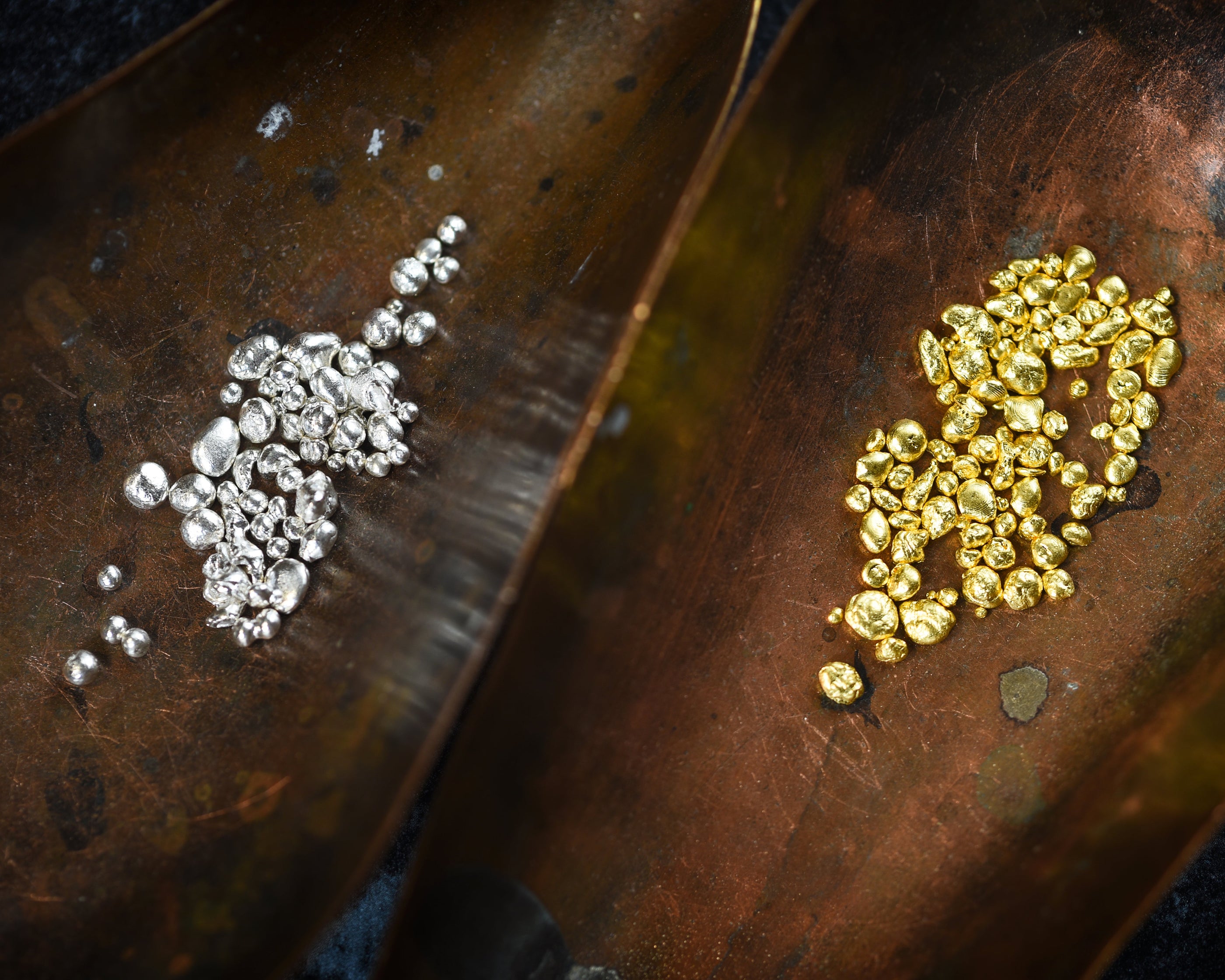 white and yellow gold nuggets sitting a wooden board