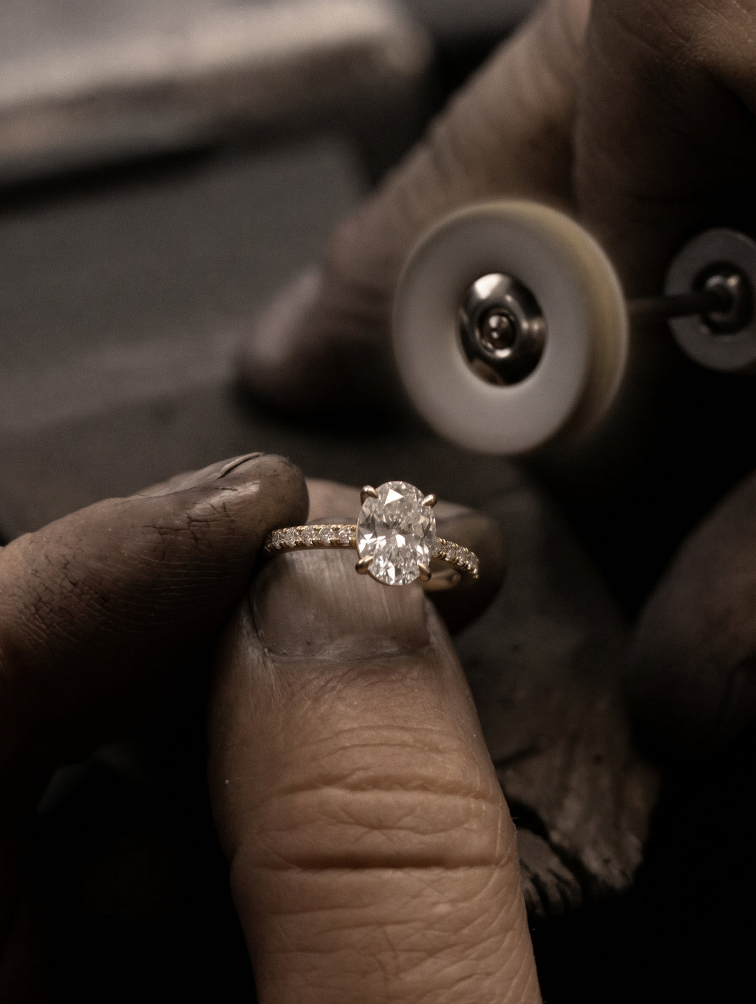 Jeweller polishing and carefully finishing The Astra Ring - Oval Solitaire with a pave band in 18K Yellow Gold | The Jewel Concierge