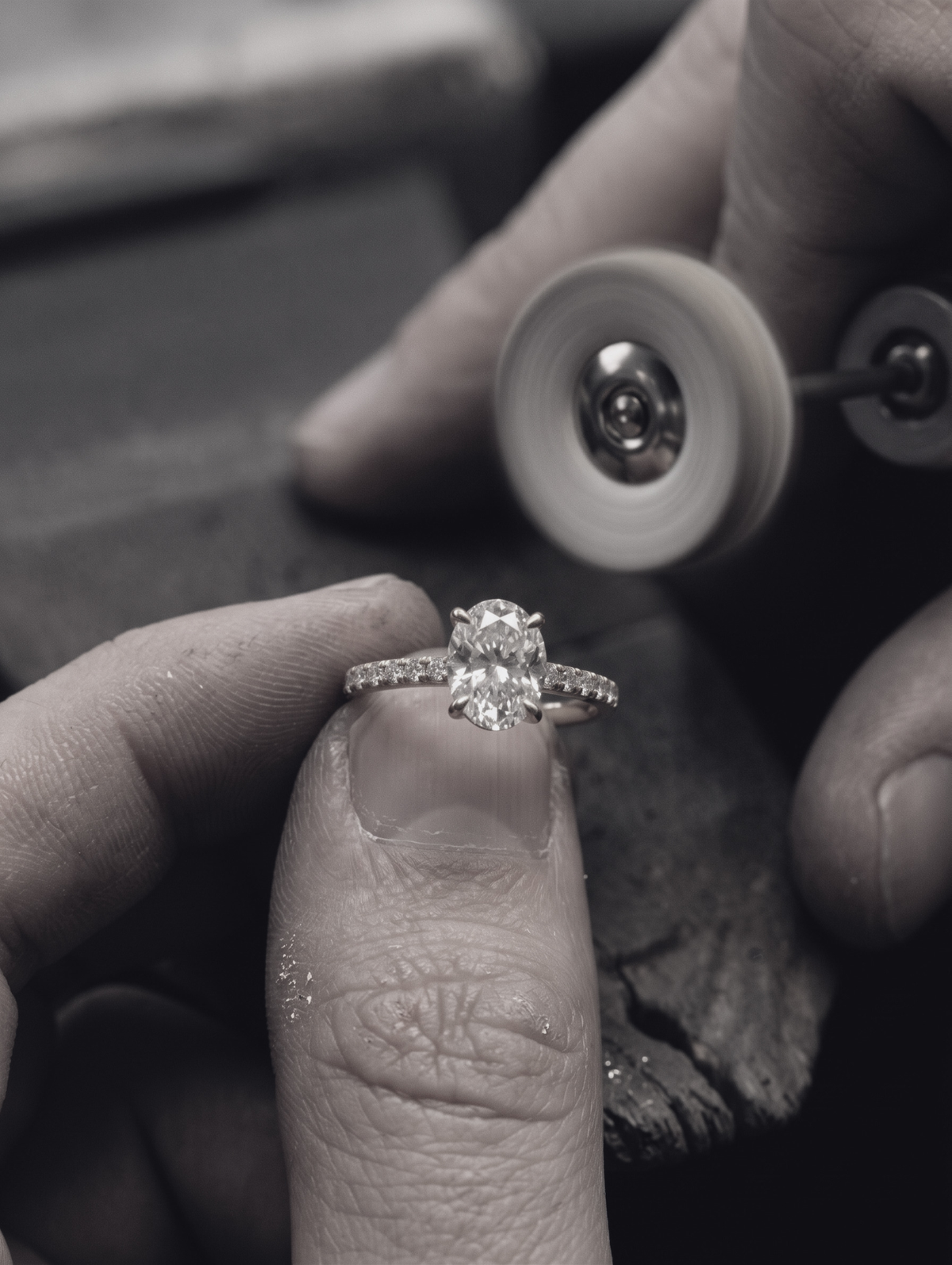 Jeweller Polishing and carefully inspecting The Astra Ring - Oval Solitaire with pave band, set in 18K Yellow Gold | The Jewel Concierge