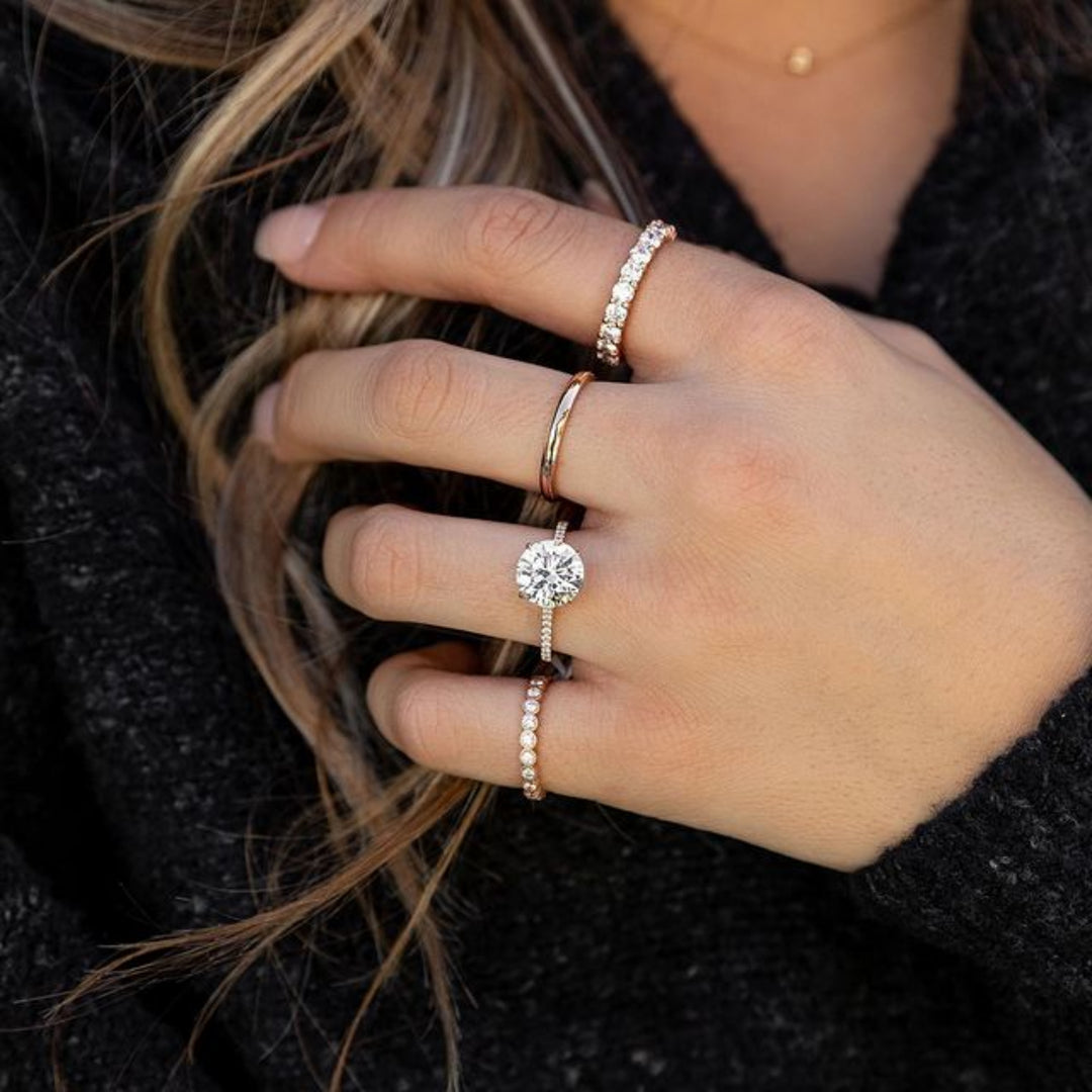 Close-up of a hand wearing multiple diamond rings on a dark background