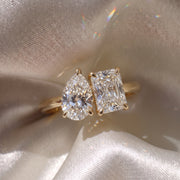 The Margot Ring — Pear and Radiant Toi Et Moi Lab-Grown Diamond Engagement Ring in Yellow Gold on a beige silk fabric | The Jewel Concierge