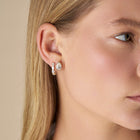Close-up of a blonde model, wearing The Aurelia Pear Cut Studs against a soft beige background - The Jewel Concierge
