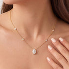 A  close up of a model wearing The Juliette Necklace in yellow gold, featuring a delicate chain with four small round bezel-set lab-grown diamonds spaced along the chain, ending with an oval-cut lab-grown diamond solitaire pendant - The Jewel Concierge