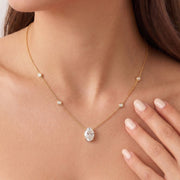 A  close up of a model wearing The Juliette Necklace in yellow gold, featuring a delicate chain with four small round bezel-set lab-grown diamonds spaced along the chain, ending with an oval-cut lab-grown diamond solitaire pendant - The Jewel Concierge