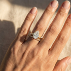 Hand wearing a diamond ring on a neutral background