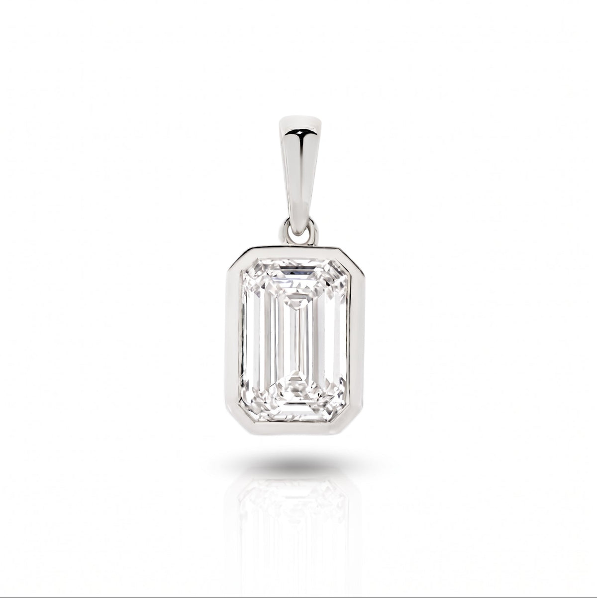 A white gold pendant featuring an emerald lab-grown diamond, set in a bezel setting against a clean white background with a soft reflection - The Jewel Concierge