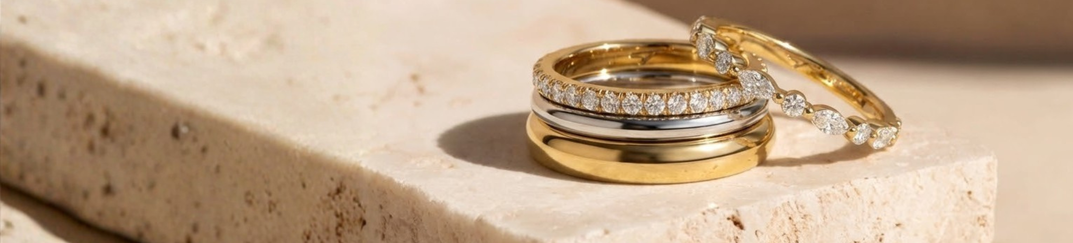 Three gold rings stacked on a light stone surface