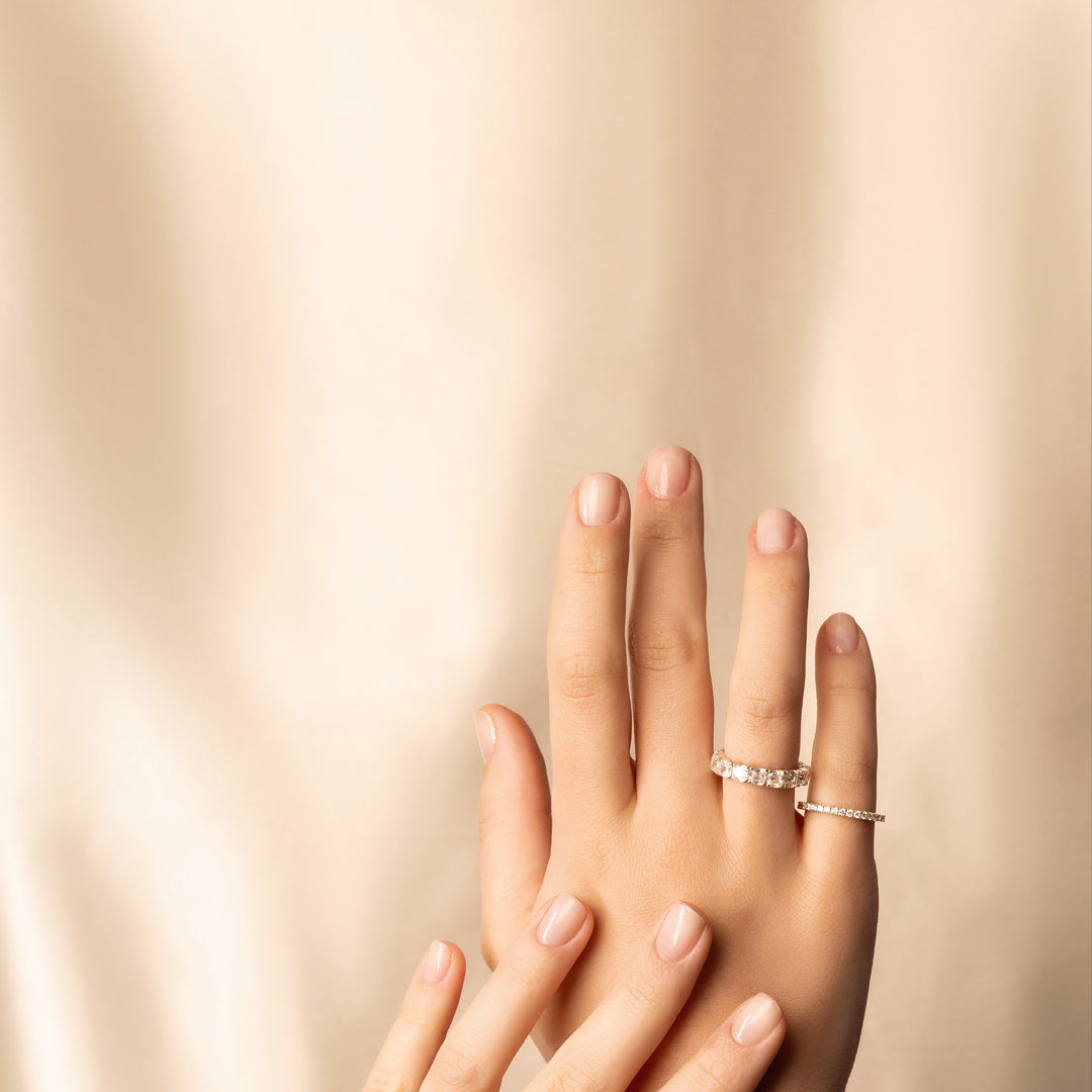 Two hands with wedding rings on a beige background
