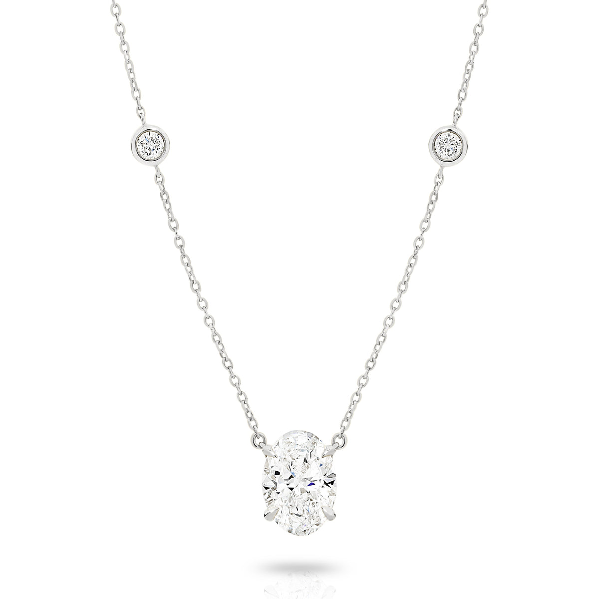 A white gold necklace featuring a delicate chain with five small round bezel-set lab-grown diamonds spaced along the chain, ending with an oval-cut lab-grown diamond solitaire pendant, shown on a white background - The Jewel Concierge