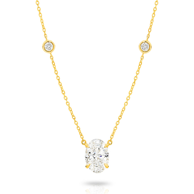 A yellow gold necklace featuring a delicate chain with five small round bezel-set lab-grown diamonds spaced along the chain, ending with an oval-cut lab-grown diamond solitaire pendant, shown on a white background - The Jewel Concierge