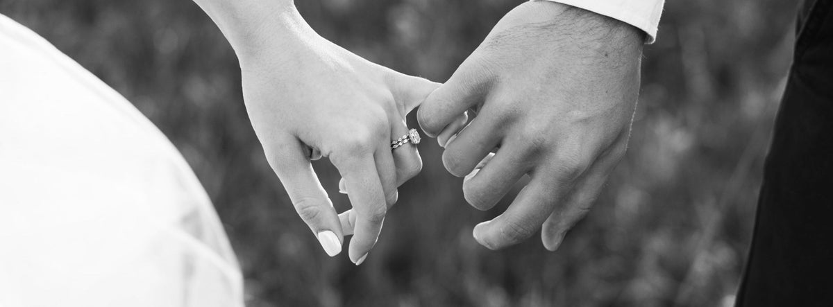 Black and white photo of two hands holding each other with a blurred background | The Jewel Concierge