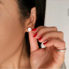 Close-up of a woman wearing diamond earrings and a ring with a blurred background