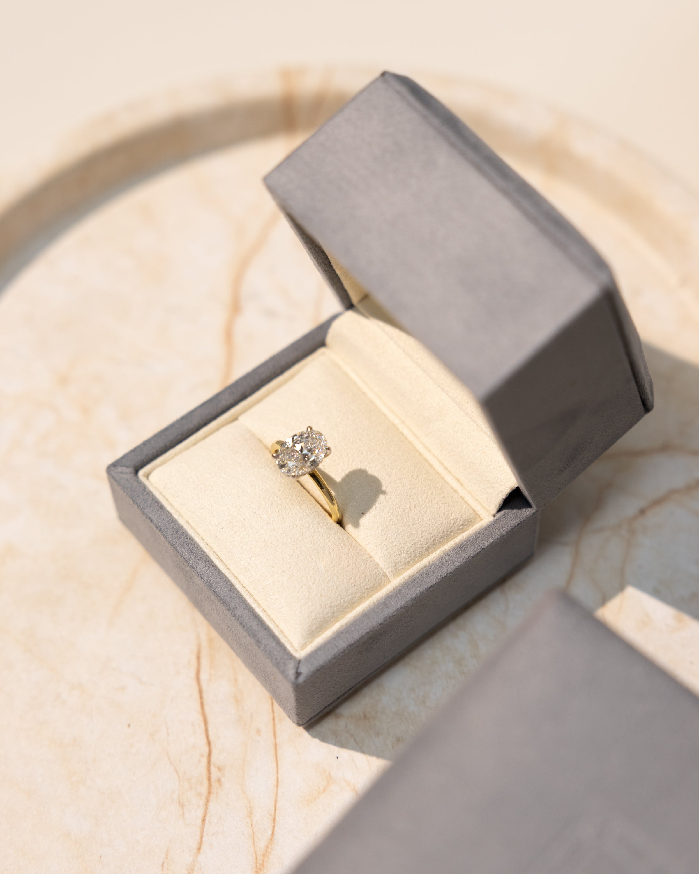 diamond engagement ring inside fancy ring box on a marble tray