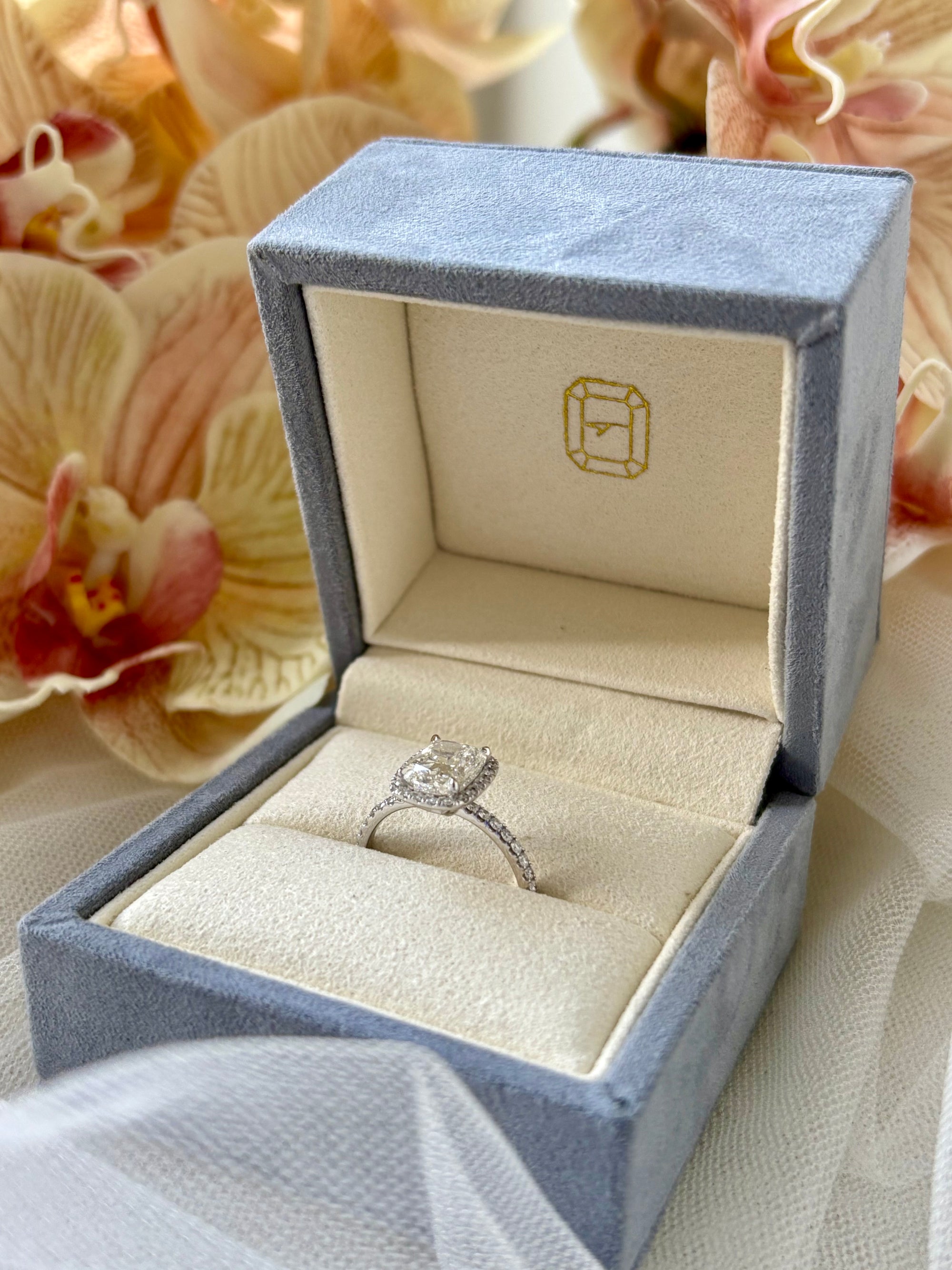 Cushion halo engagement ring in a signature The Jewel Concierge ring box with a soft floral background