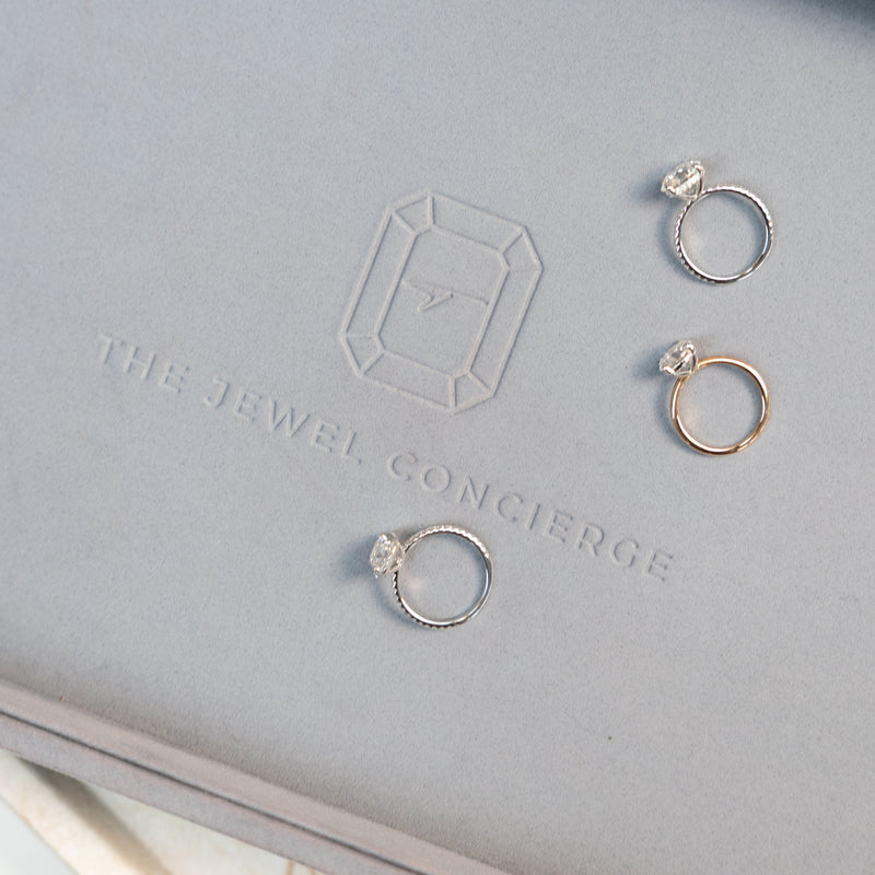 Three diamond rings on a jewellery tray with 'The Jewel Concierge' branding.