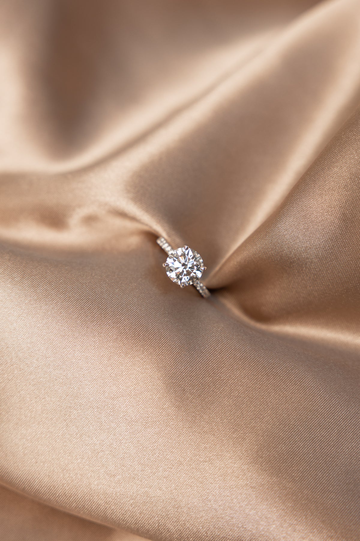 Lab-grown Diamond solitaire engagement ring on a beige satin fabric