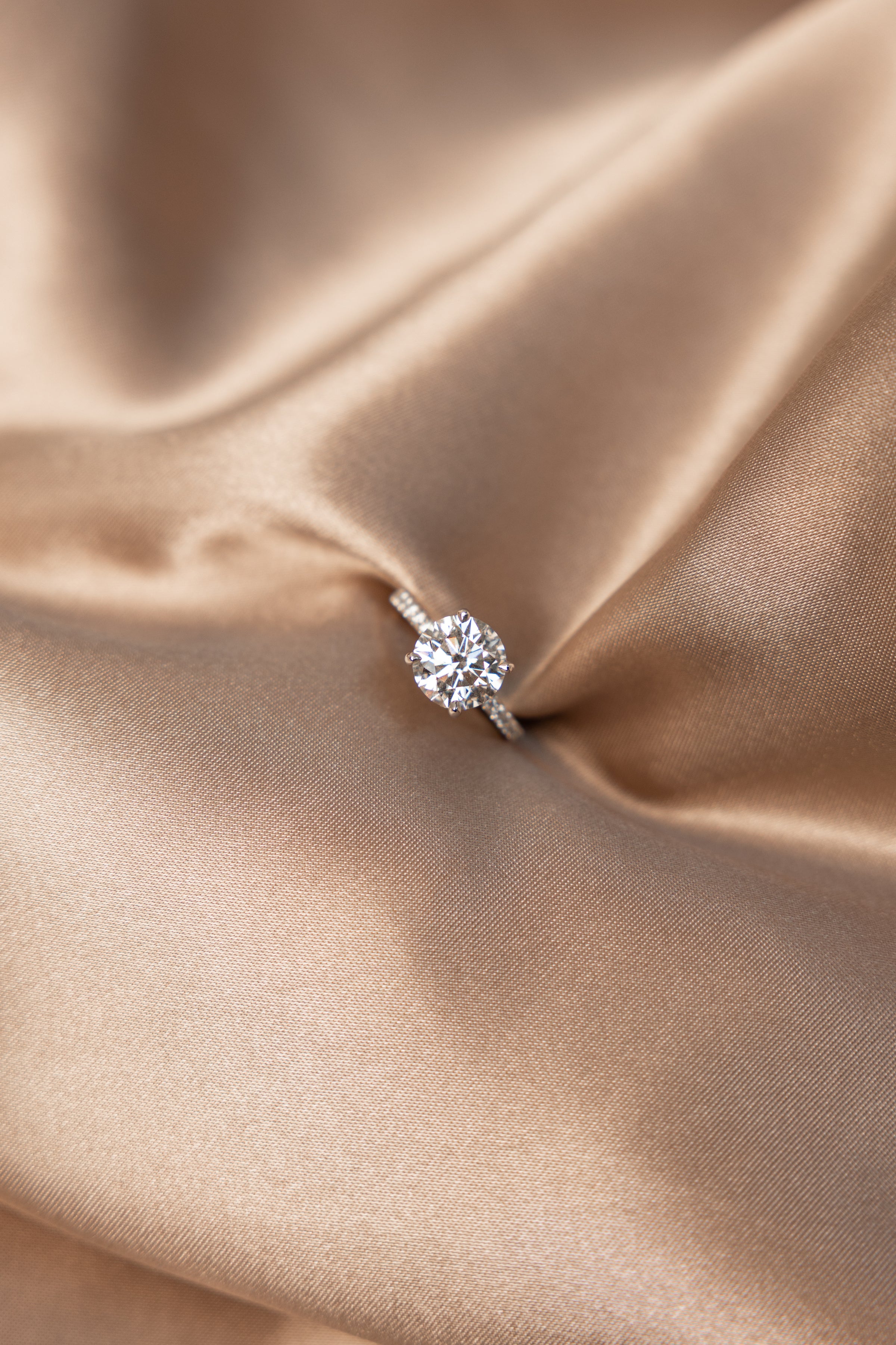 Lab-grown Diamond solitaire engagement ring on a beige satin fabric